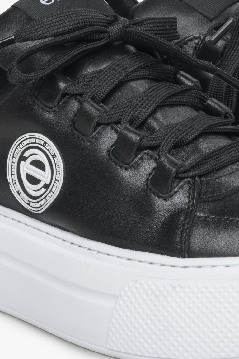 Women's black sneakers made of genuine leather - close-up on details.