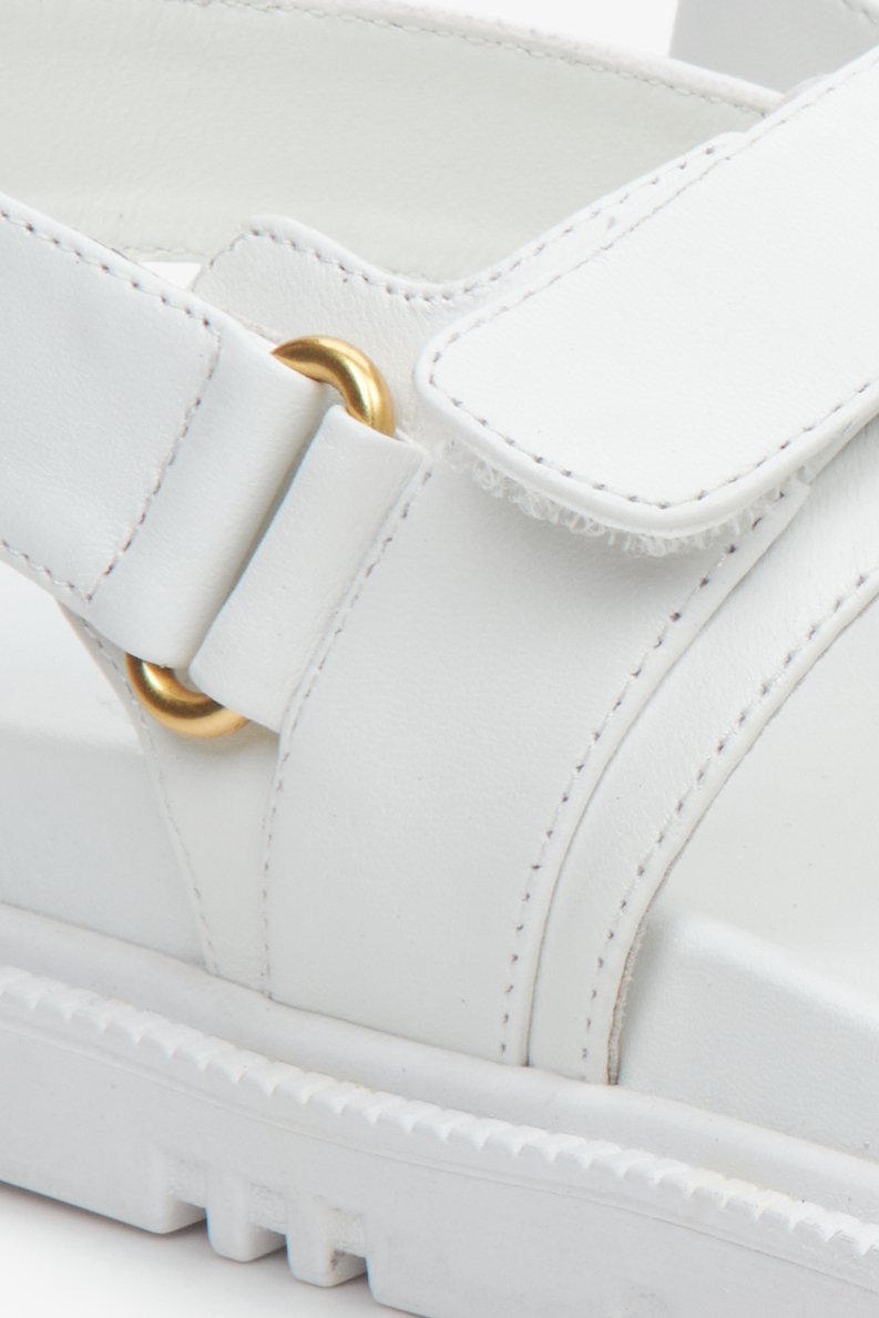 Women's white leather comfortable sole sandals with golden elements - close-up on the details.