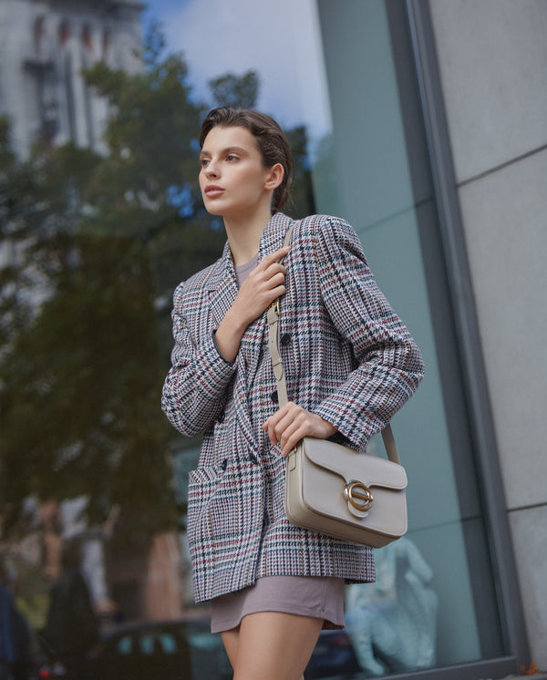 Women's small grey and beige handbag with gold hardware made of leather by Estro - presentation on a model.