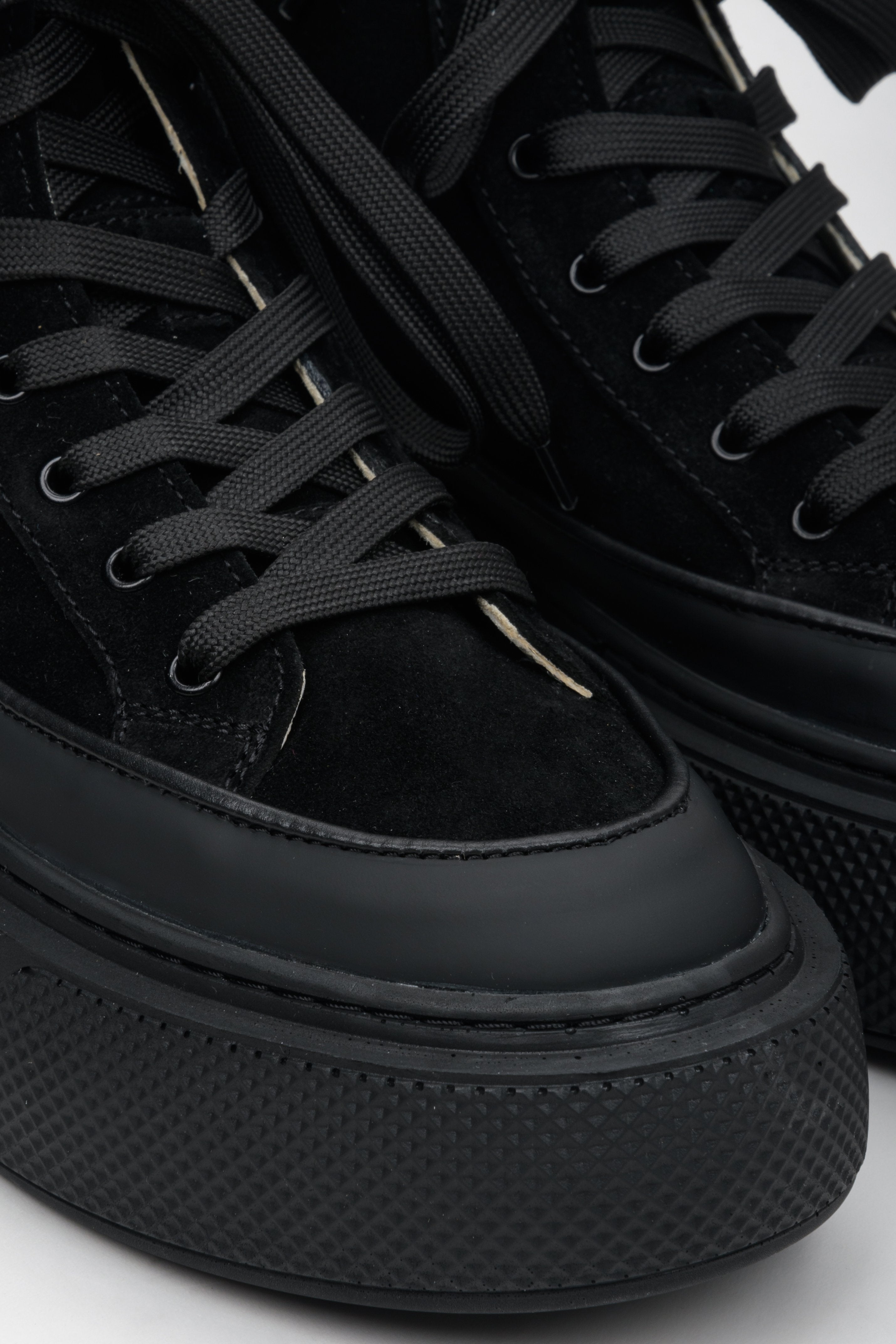 High-top women's black sneakers made of leather and velour by Estro - close-up on the rounded toe of the shoe.