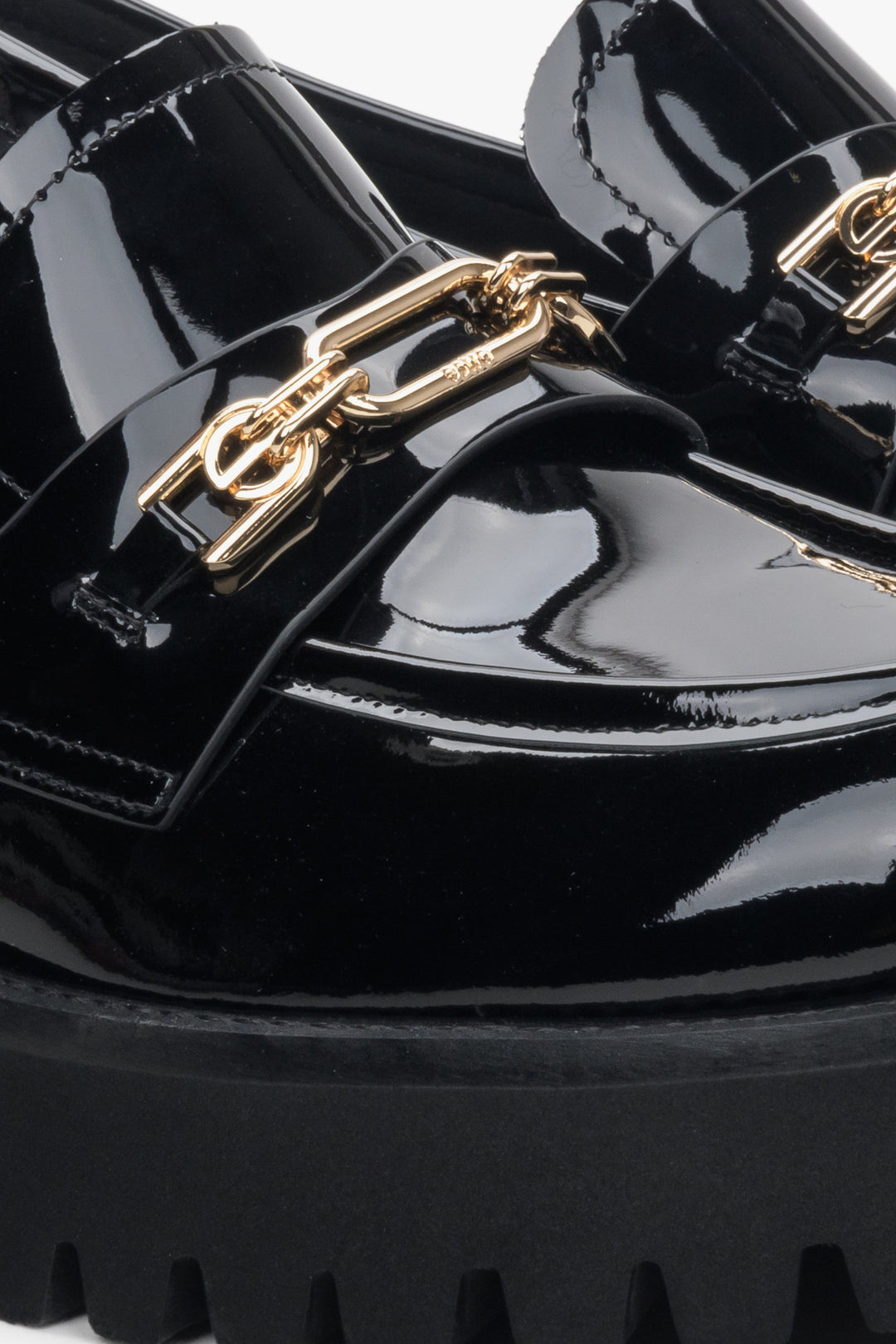 Women's black patent leather moccasins by Estro - close-up on the gold buckle.