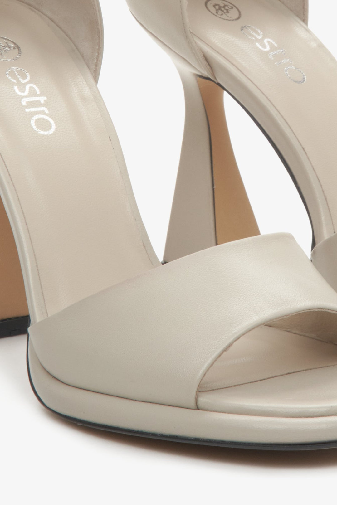 Women's sandals in beige: made of leather, on a stiletto heel, fastened at the ankle. Close-up of the details.